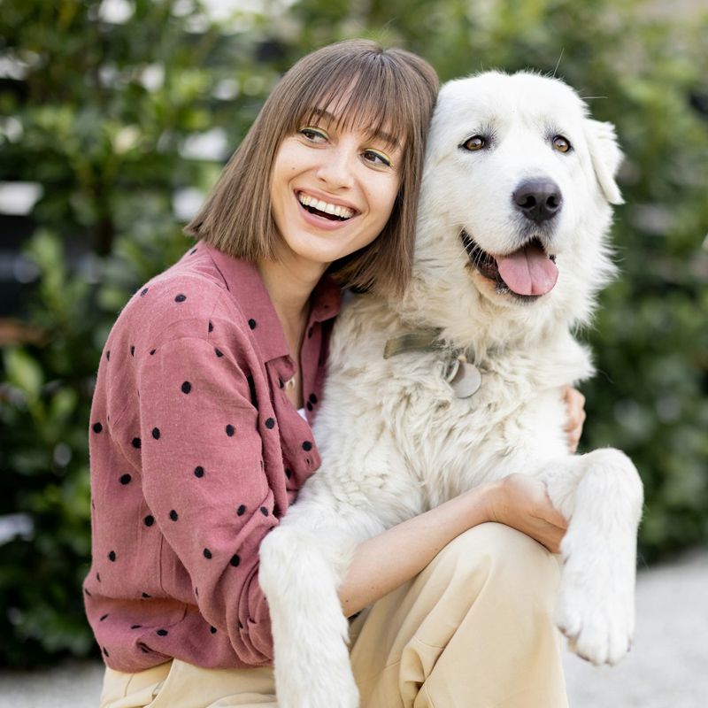 a happy women holding a white colour dog